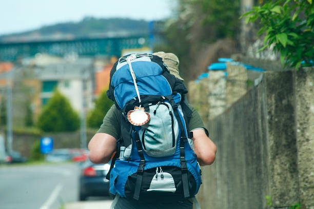 Rear view of pilgrim walking along the portuguese 'camino de santiago' with backpack, traditional  scallop shell symbol, Redondela, Pontevedra province, Galicia, Spain.