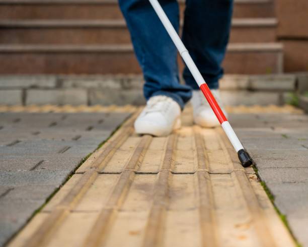 istock A blind woman walks outdoors using a cane along a tactile yellow tile. 2197194537