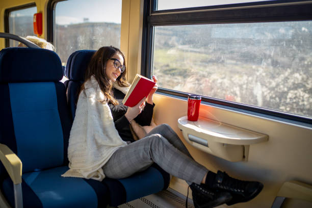 istock Young female passenger reading book while traveling by train 2197195824