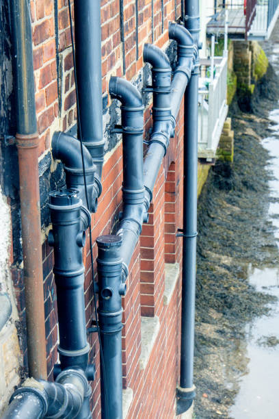 Black pipes secured to the side of a building create a network to take waste and water to the ground below.