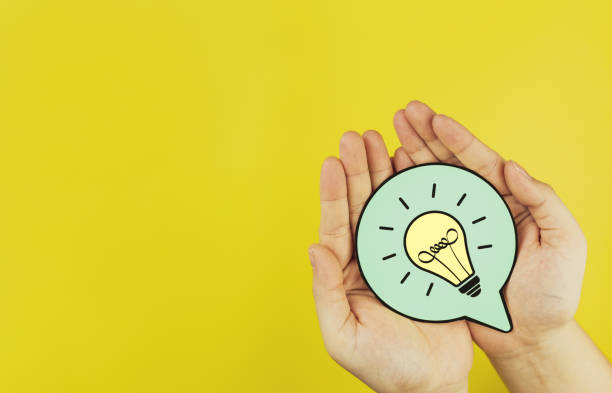 istock Paper light bulb in hand on yellow background with copy space. Concepts of creativity, innovation 2197198194