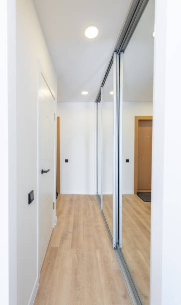 istock Modern Hallway Interior with Wooden Floor and Mirrored Wardrobe Doors. Bright and contemporary interior design of a hallway featuring wooden flooring, a white door. Scandinavian Style 2197199278