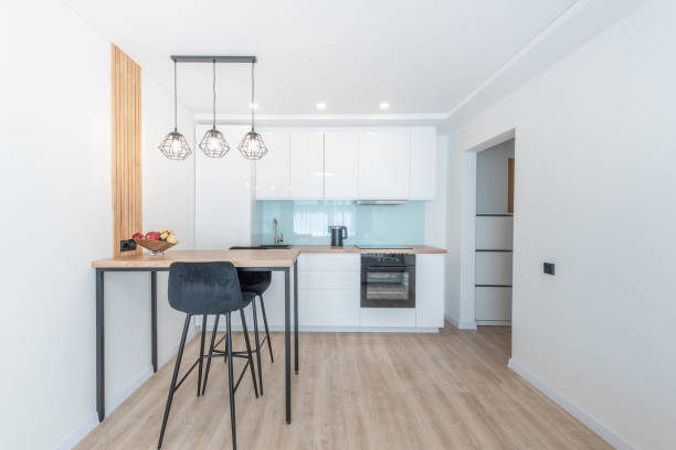 istock Modern Minimalistic Scandinavian Kitchen Interior With Bright Lighting and Stylish Furniture Design. Bright modern kitchen with contemporary furniture design featuring a wooden countertop, stools 2197199429