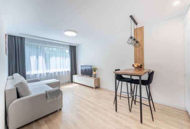 istock Home Interior. Bright and modern living room interior featuring Scandinavian design elements and minimalistic furniture, highlighting light walls, large windows, and a cozy seating and dining area. 2197199447
