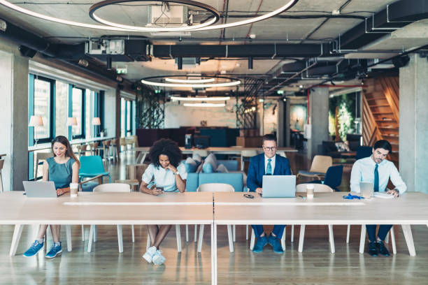 istock Business concept with four people sitting at a long desk and using mobile devices 2197200079