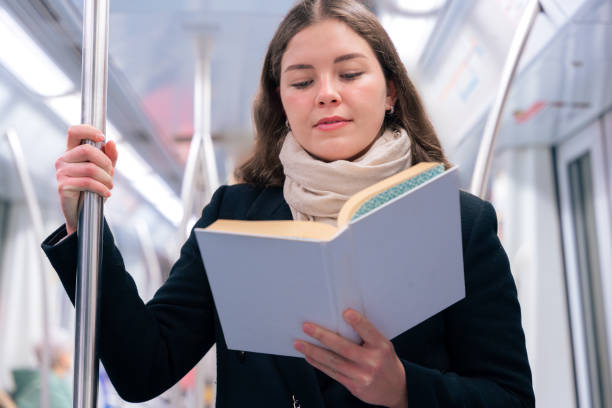 istock Young Woman Reading a Book While Standing on a Subway Train 2197200609