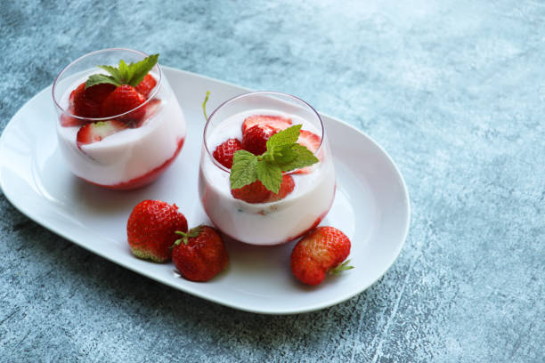 istock Red strawberries with whipped cream dessert on blue background 2197202081