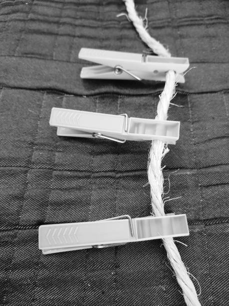 A solitary wooden clothespin clipped to a tight rope with a blurred natural background, offering space for text.