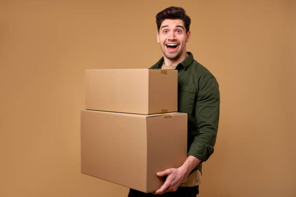 istock A man is carrying several boxes against a warm beige background, showcasing his effort 2197203604