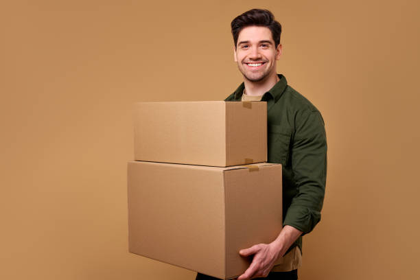 istock A man is carrying several boxes against a warm beige background, showcasing his effort 2197203608