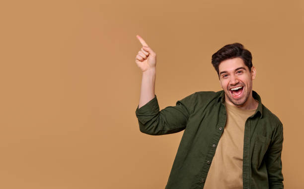 istock A Cheerful Young Man Pointing Exuberantly with Enthusiasm Against a Vibrant Warm Background 2197203630