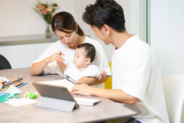istock A woman holding a baby and a man operating a computer 2197203775