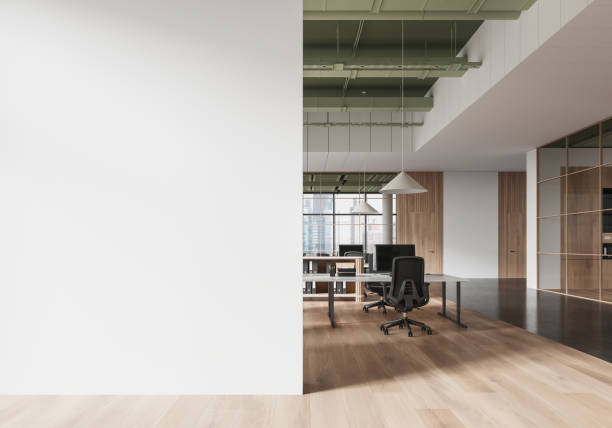 istock Empty white wall mockup in modern office space with minimalist design and wood accents, featuring desks and chairs in the background. 3D Rendering 2197206167