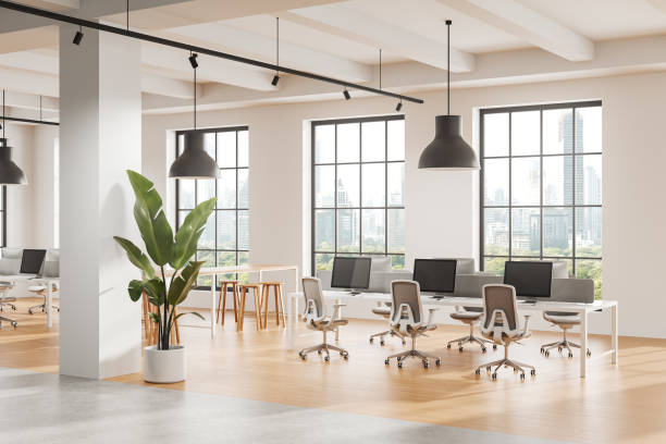 istock Modern open office space with desks, chairs, computers, and large windows overlooking cityscape. 3D Rendering 2197206559