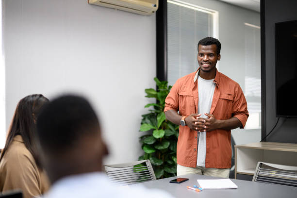 istock Young man Standing in boardroom presenting and talking to colleagues 2197207762