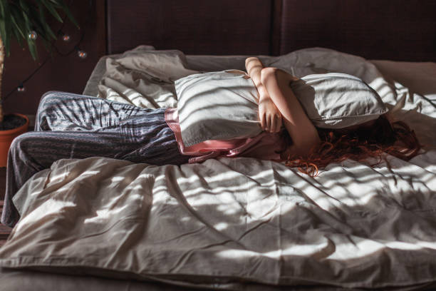 istock Sad young woman lying in bed 2197212099