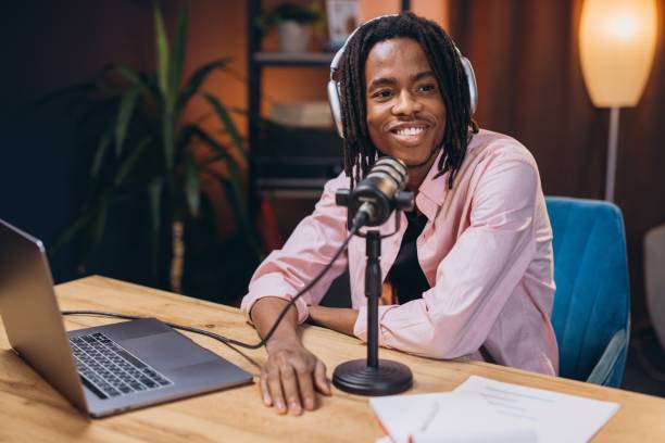 istock Happy young african american man recording podcast using microphone and laptop at home studio 2197212444