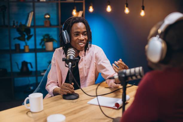 istock Two young podcasters wearing headphones and speaking into microphones while recording a podcast episode in a studio 2197212704