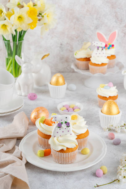istock Easter cupcakes are decorated with cream, sugar bunnies, chocolate eggs, jelly carrots on a white plate. Easter food composition. Copy space. 2197213071