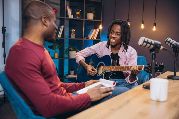 istock African American musician performing acoustic guitar while engaging with interviewer during podcast recording session 2197213246