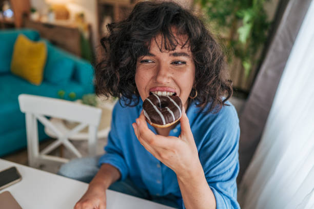istock A woman sitting at a dining table,enjoying a rich, chocolate doughnut, her expression pure pleasure. 2197213440