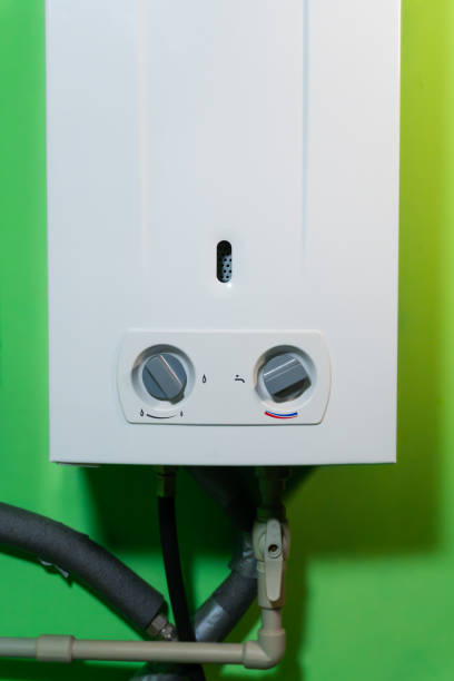 istock Combi gas boiler against a green wall – a compact heating device with a white body and two temperature control knobs. 2197213595