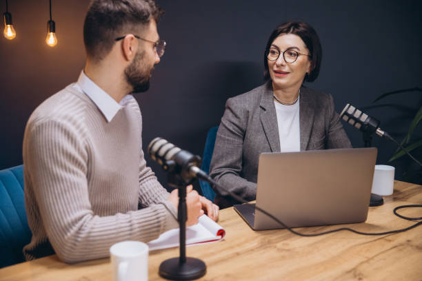 istock Two podcasters, a man and a woman, are recording a show in a professional studio, using microphones and a laptop 2197215688