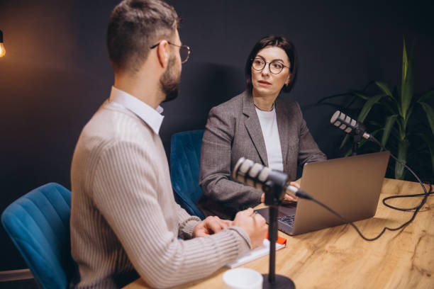 istock Two content creators recording a podcast in a professional studio, using microphones and a laptop 2197215720
