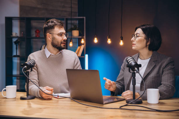 istock Two content creators recording their podcast using professional microphones and a laptop in a studio with soft lights 2197215775