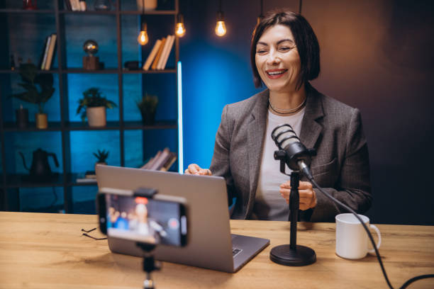 istock Smiling female podcaster speaking into microphone during professional audio recording session 2197215779