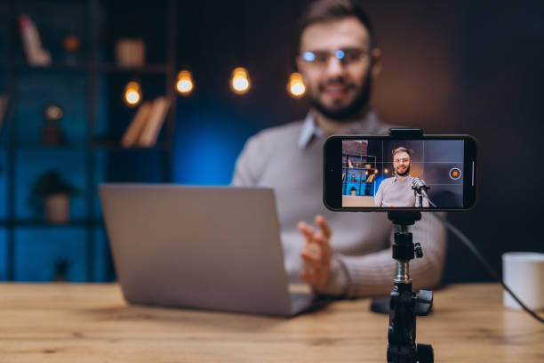 istock Influencer recording podcast in home studio using smartphone and microphone, laptop on desk 2197215925