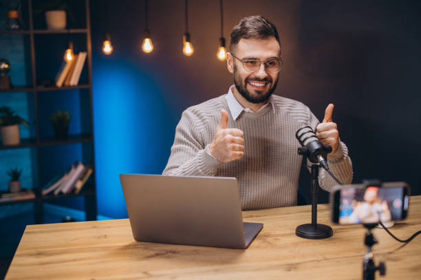 istock Happy podcaster giving a thumbs up while recording engaging content in a home studio, surrounded by modern technology and creativity 2197216008