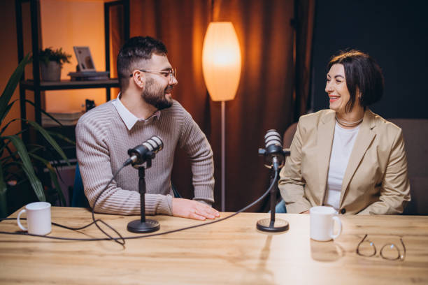 istock Professional podcasters speaking into microphones, collaborating and smiling during recording session for digital audio broadcast 2197216042
