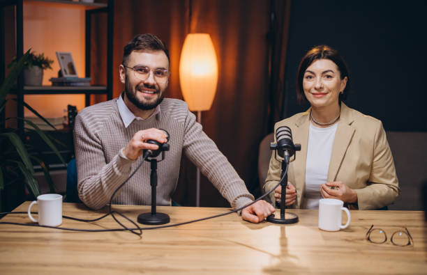 istock Professional podcast duo discussing content, speaking into microphones while seated in soundproofed recording studio environment 2197216158