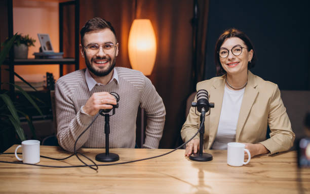 istock Two smiling podcasters engaging in lively conversation while recording audio content in a professional studio setting 2197216166