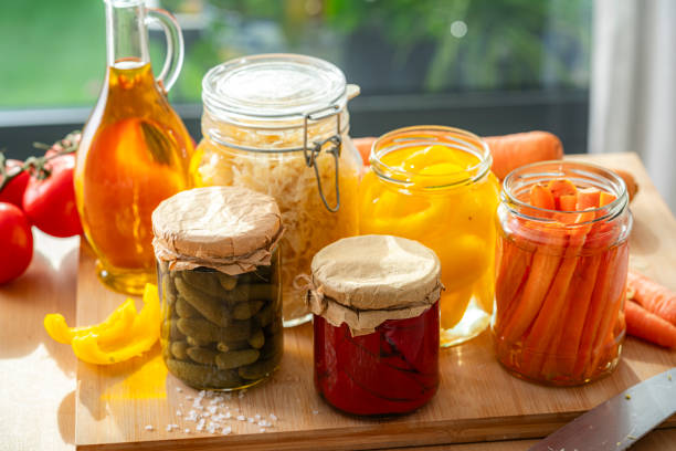 Various fermented and pickled vegetables in glass jars on kitchen table. High anle view