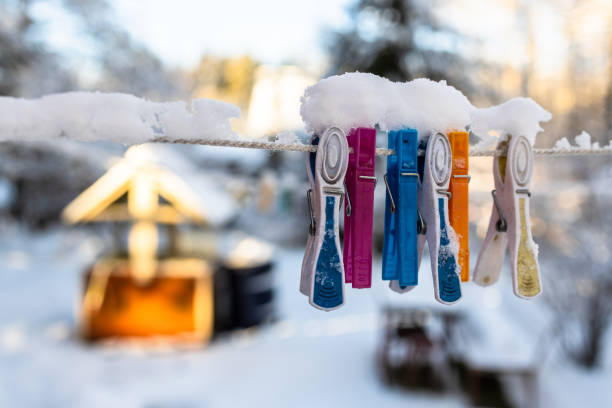 snow-covered clothespins on clothesline closeup in country yard with well in sunny winter evening