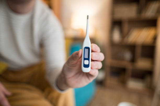Close up of a man's hand holding a thermometer