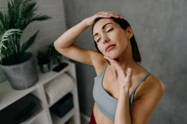 Young woman practicing yoga and stretching neck in bathroom