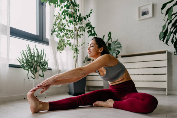 istock Young woman practicing yoga and stretching legs at home 2197225487