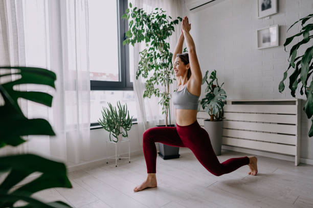 istock Young woman practicing yoga at home in warrior pose 2197225505