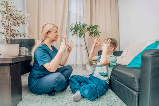 istock female therapist and boy practicing hand gestures in therapy session, cozy home setting, concept of child development and alternative communication 2197231582