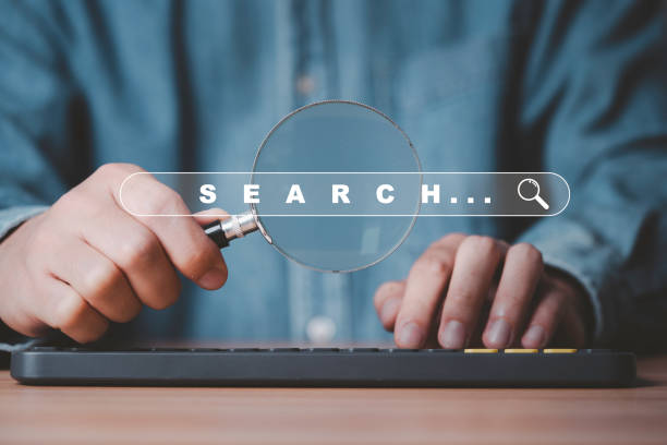 istock Businessman hold magnifier glass and use computer keyboard for search engine optimization or SEO , Marketing searching business and web browser data trend concept. 2197232626