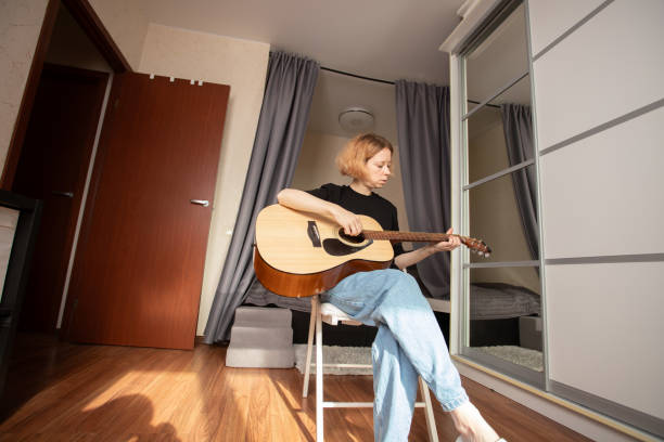 istock music lessons, Woman learning guitar, sitting in a studio, strumming classic melodies, studying music theory 2197233081