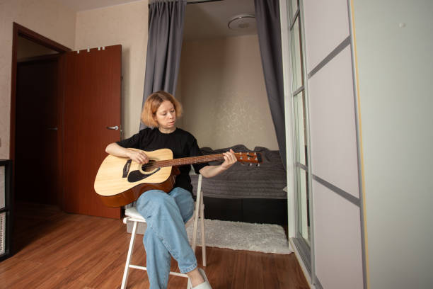 istock music lessons, Woman learning guitar, leisure activity, practicing melodies, building confidence as a guitarist 2197233095