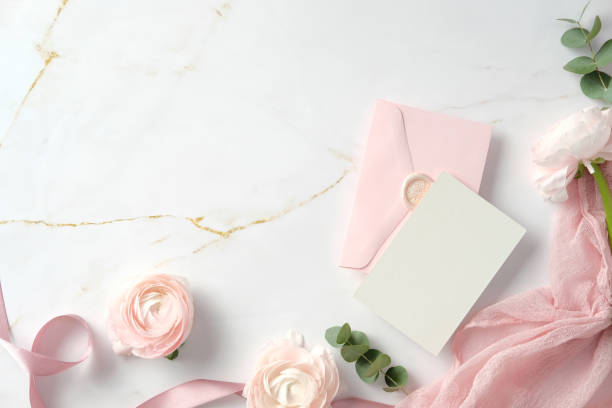 istock Elegant flat lay with a pink envelope, blank card, and delicate flowers on a marble background. Stylish wedding stationery set, top view 2197233402