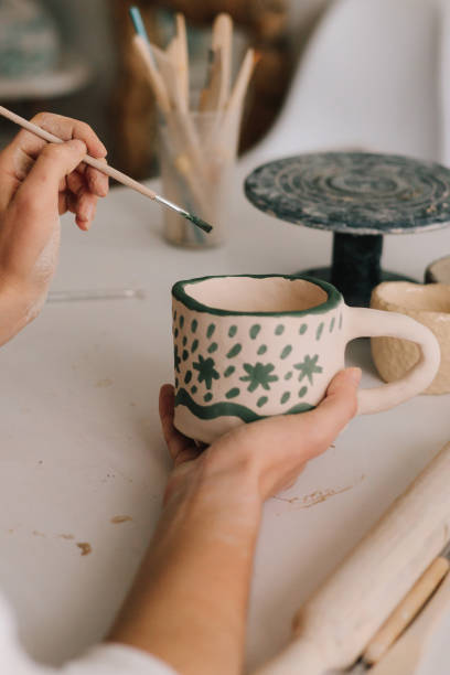 istock Artist is making decoration on the clay ceramic mug after oven firing. Design earthenware cup with a traditional pattern. 2197233502