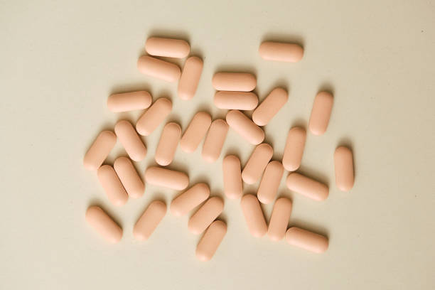 Peach-colored pills scattered on a beige background in a macrophotography shot