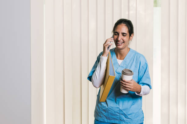 istock Smiling nurse talking on phone, holding file and coffee 2197236359