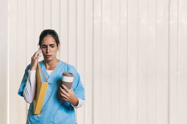 istock Stressed nurse talking on the phone and holding a coffee and a folder 2197236472